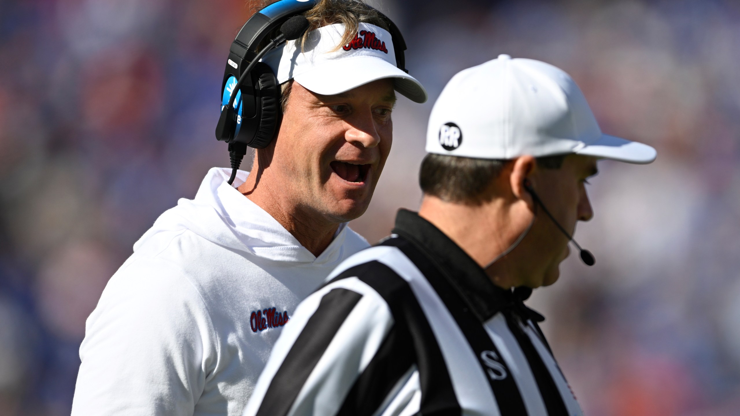 Mississippi head coach Lane Kiffin, left, questions an official on the sideline during the first half of an NCAA college football game against Florida, Saturday, Nov. 23, 2024, in Gainesville, Fla. (AP Photo/Phelan M. Ebenhack)