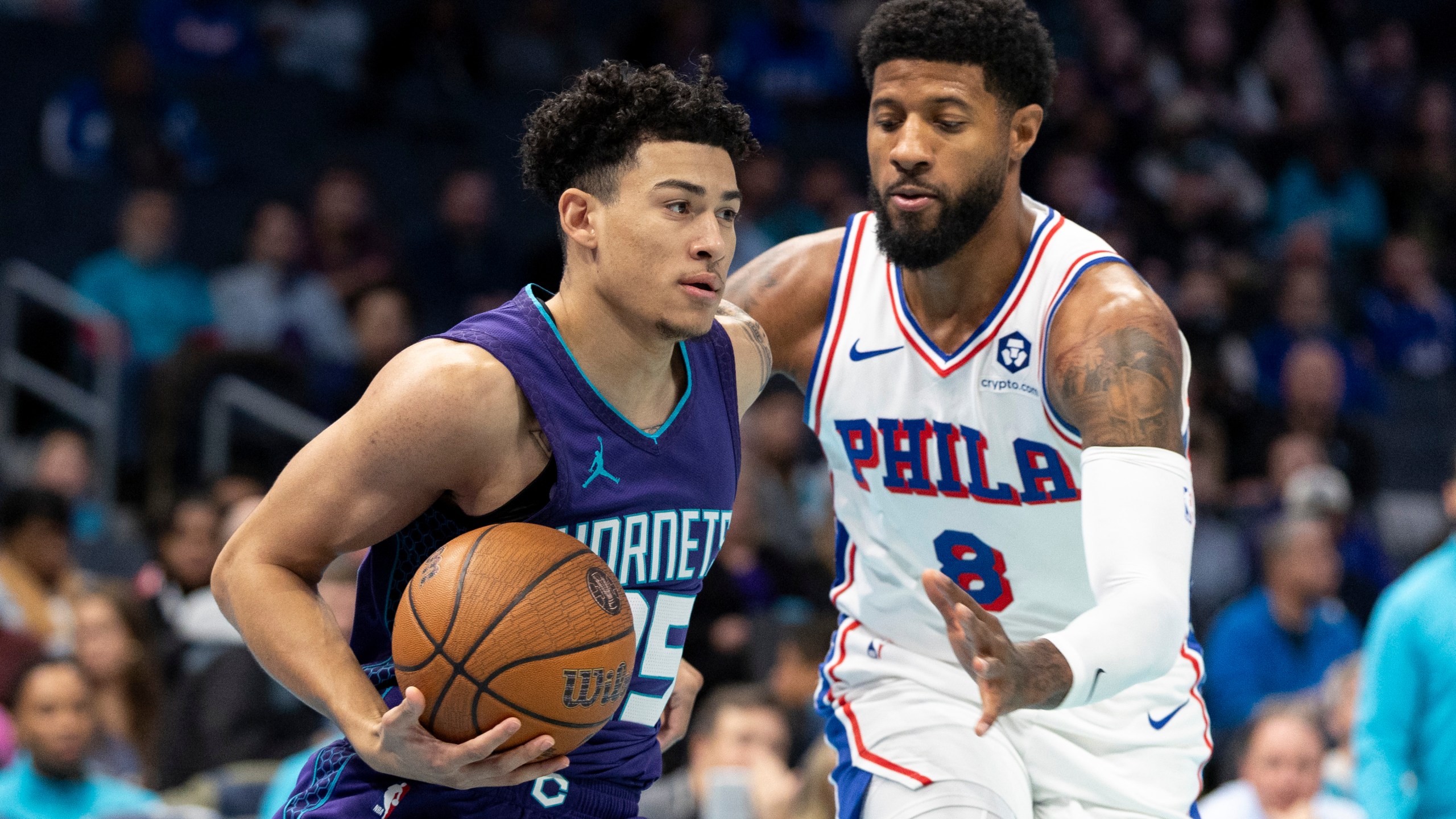 Charlotte Hornets guard KJ Simpson, left, drives against Philadelphia 76ers forward Paul George during the first half of an NBA Cup basketball game in Charlotte, N.C., Tuesday, Dec. 3, 2024. (AP Photo/Nell Redmond)