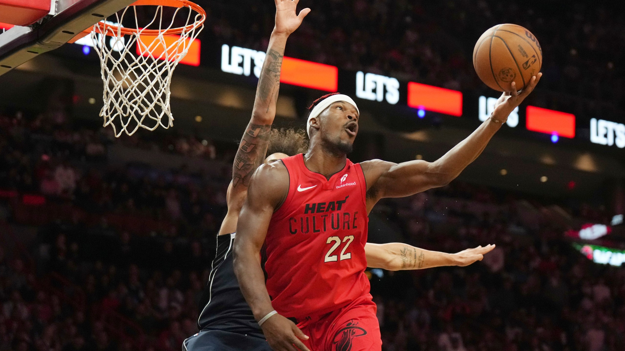 Miami Heat forward Jimmy Butler (22) spins, shoots and makes a basket without looking at the basket as Dallas Mavericks center Dereck Lively II, back left, defends during the second half of an NBA basketball game, Sunday, Nov. 24, 2024, in Miami. (AP Photo/Jim Rassol)