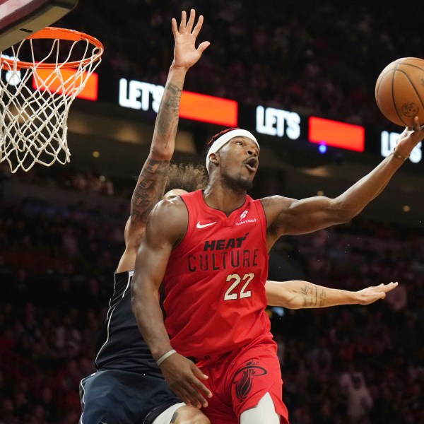 Miami Heat forward Jimmy Butler (22) spins, shoots and makes a basket without looking at the basket as Dallas Mavericks center Dereck Lively II, back left, defends during the second half of an NBA basketball game, Sunday, Nov. 24, 2024, in Miami. (AP Photo/Jim Rassol)