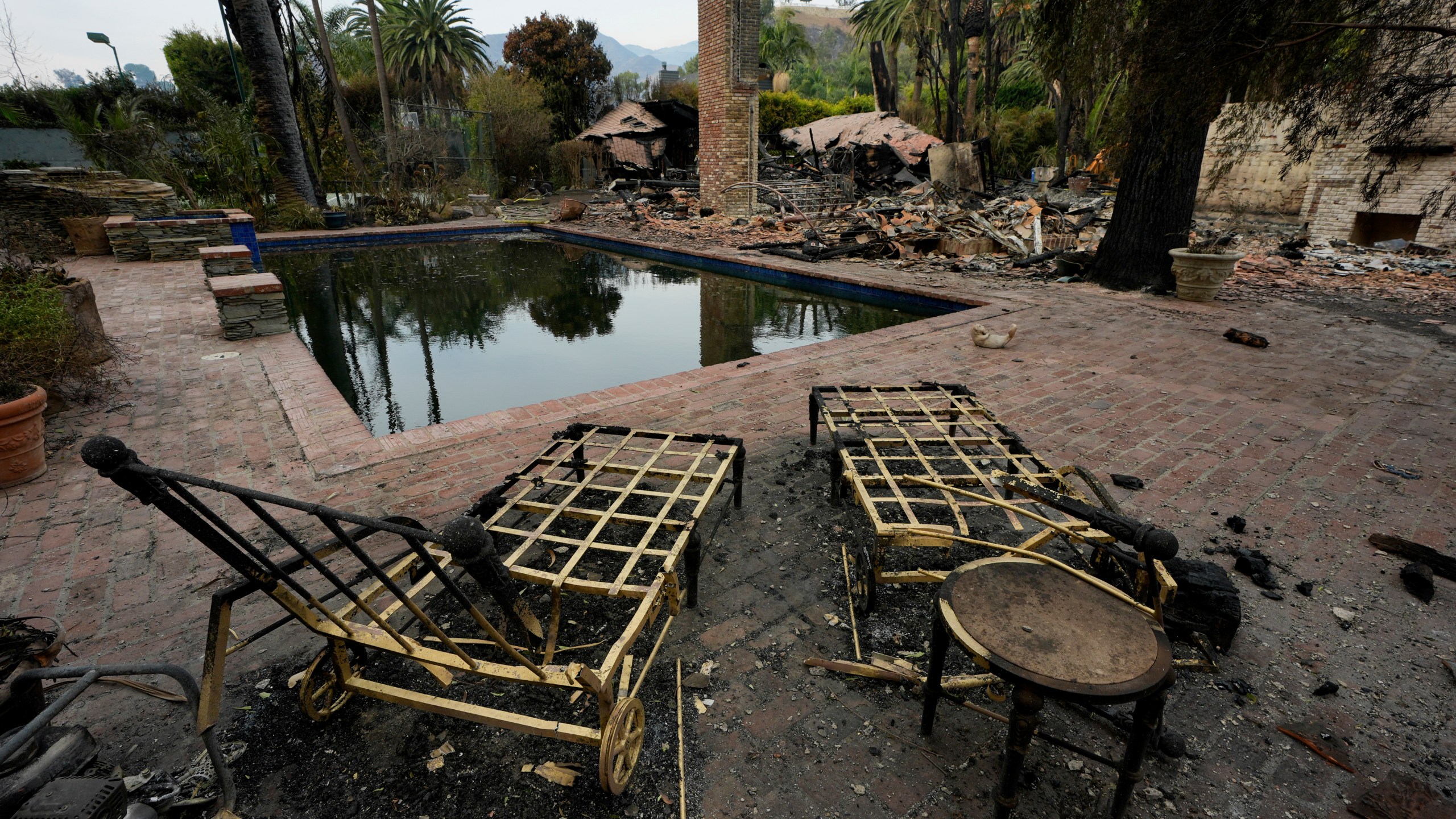 Burned outdoor furniture is left behind on a property after the Franklin Fire swept through, Wednesday, Dec. 11, 2024, in Malibu, Calif. (AP Photo/Damian Dovarganes)