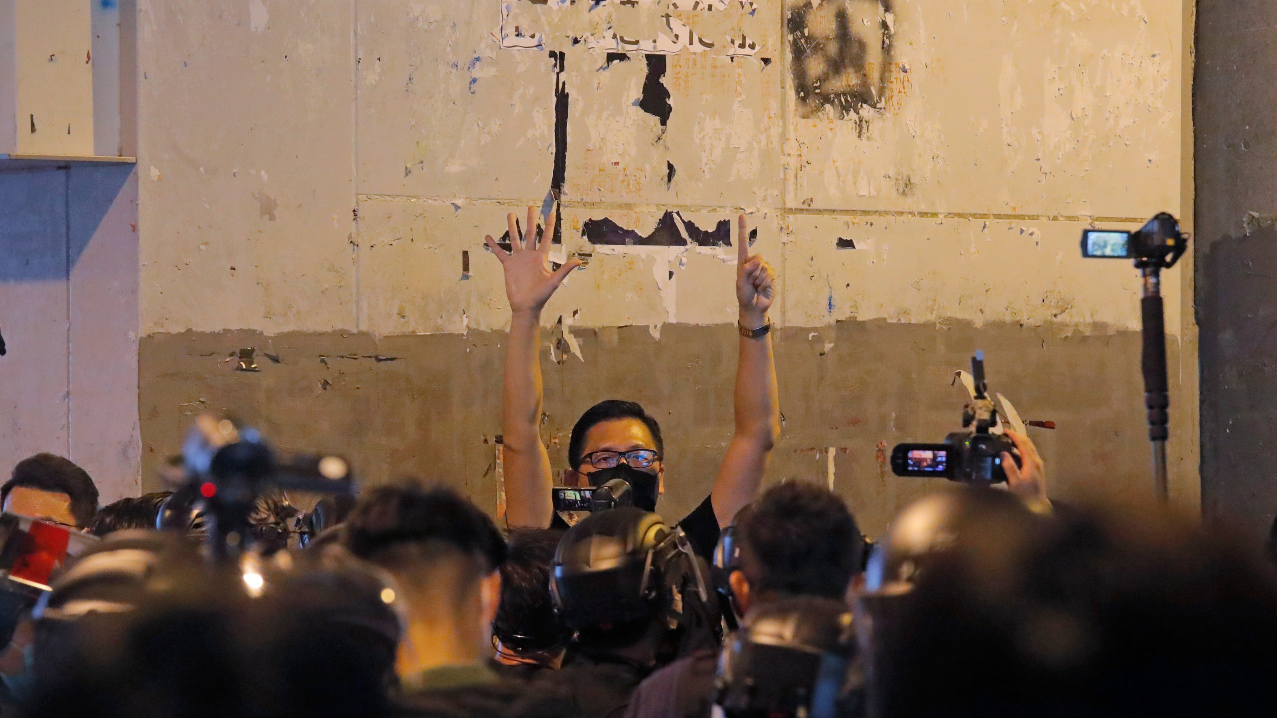 FILE- A pro-democracy lawmaker Lam Cheuk-ting, center, gestures with five fingers, signifying the "Five demands - not one less" as he is surrounded by riot police during a news conference to mark one-year anniversary of the Yuen Long subway attack at the subway station in Hong Kong, July 21, 2020. (AP Photo/Kin Cheung, File)