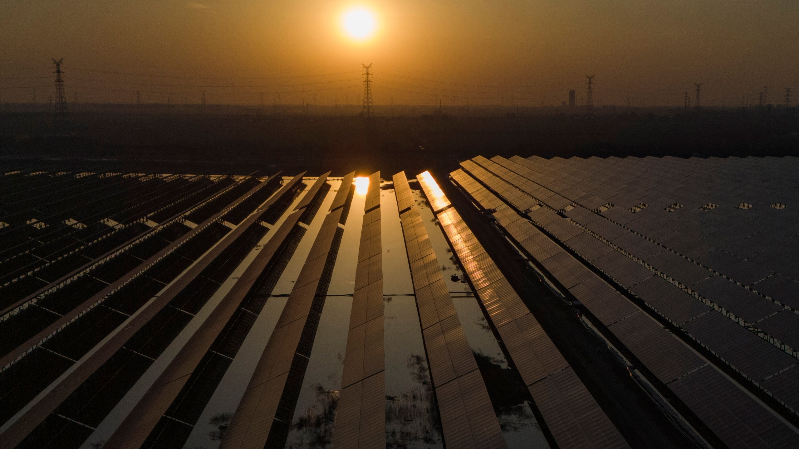 The sun sets over electric pylons along a solar farm near Weifang in eastern China's Shandong province on March 22, 2024. (AP Photo/Ng Han Guan)