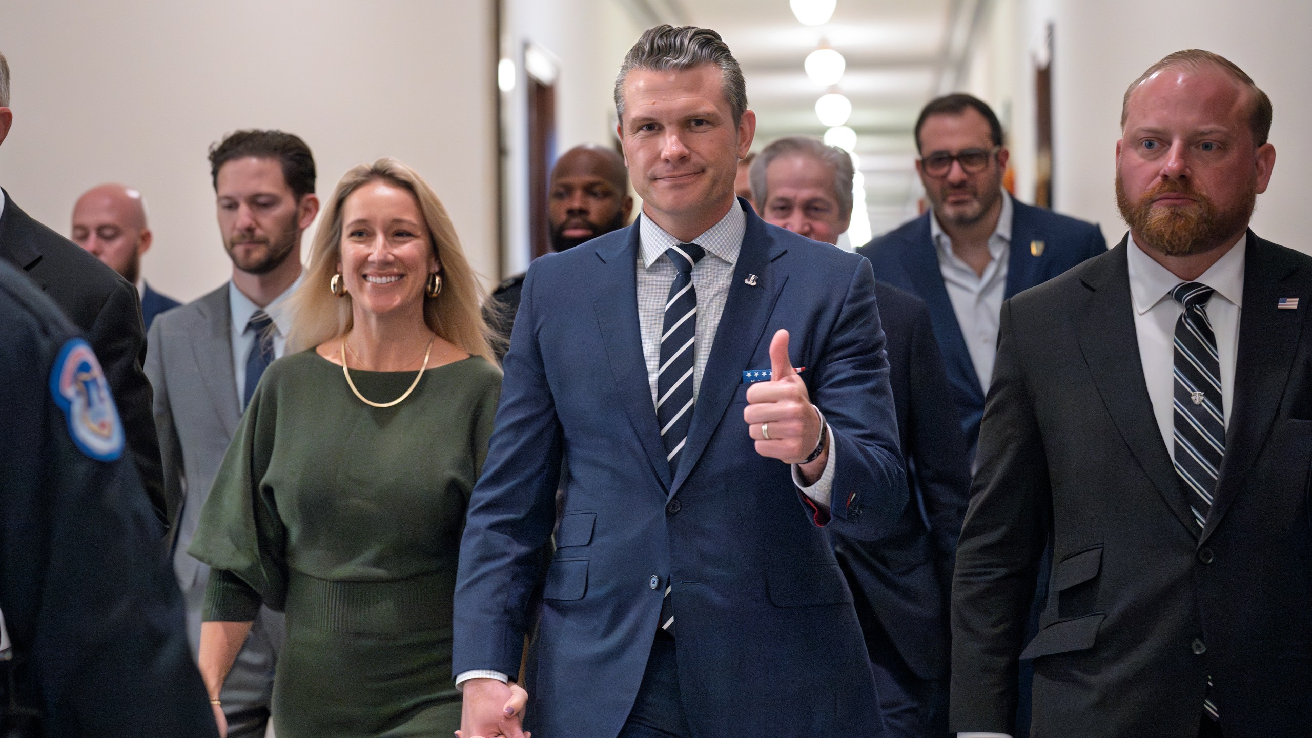 Pete Hegseth, President-elect Donald Trump's nominee to be Defense Secretary, gives a thumbs-up as he walks with his wife Jennifer Rauchet, left, to meet with Sen. Joni Ernst, R-Iowa, a member of the Senate Armed Services Committee, at the Capitol in Washington, Monday, Dec. 9, 2024. (AP Photo/J. Scott Applewhite)