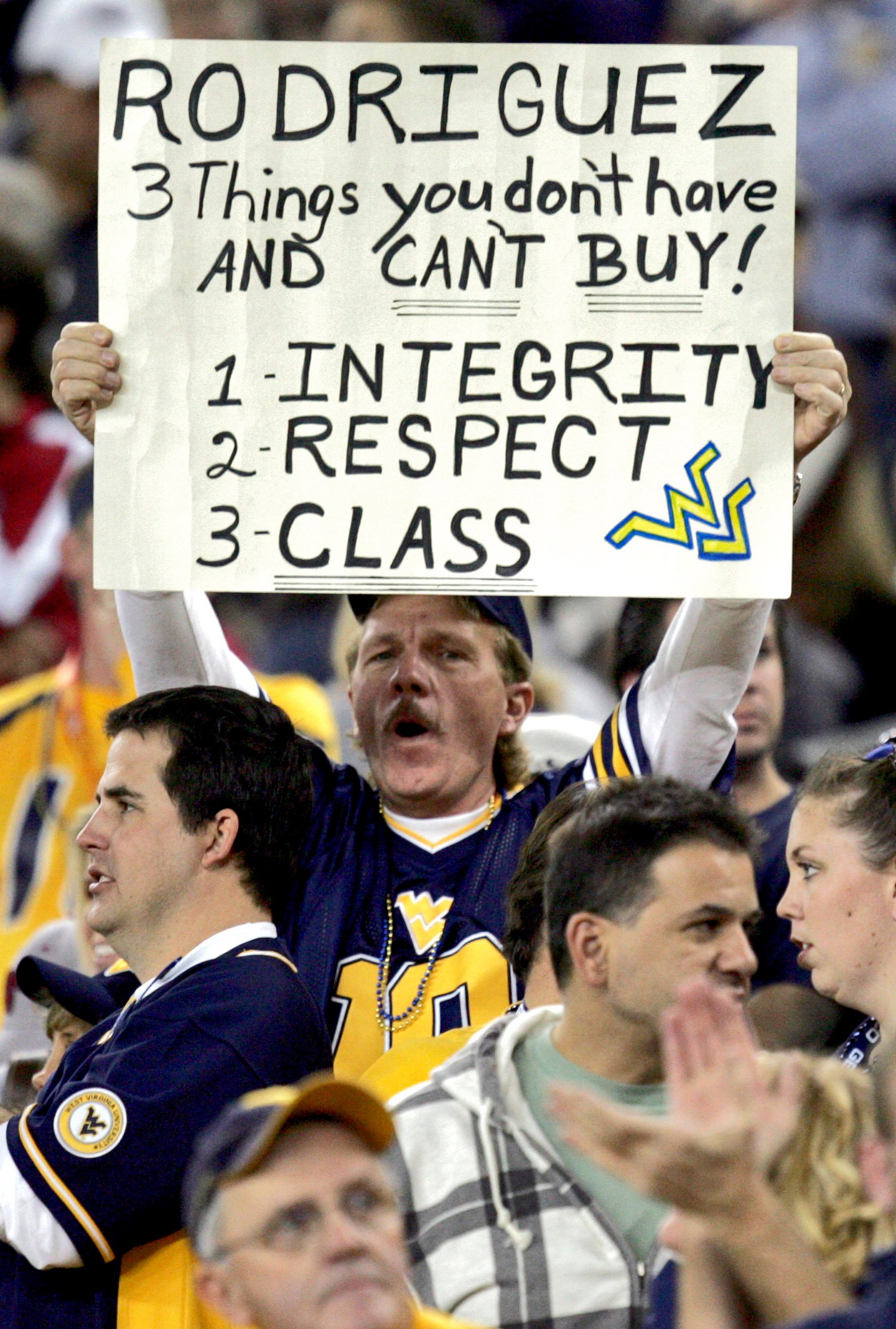 FILE - A West Virginia fan holds a sign referencing former head coach Rich Rodriguez during the first half of the Fiesta Bowl college football game against Oklahoma, Wednesday, Jan. 2, 2008 in Glendale, Ariz. (AP Photo/Matt York, File)