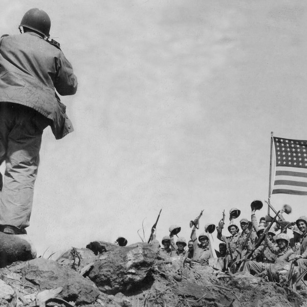 In this image provided by the U.S. Marine Corps, Marines of the 28th Regiment, 5th Division, AP photographer Joe Rosenthal photographs soldiers in front of the U.S. flag atop Mt. Suribachi, Iwo Jima, Japan, Feb. 23, 1945. (USMC/Pfc. Bob Campbell via AP)