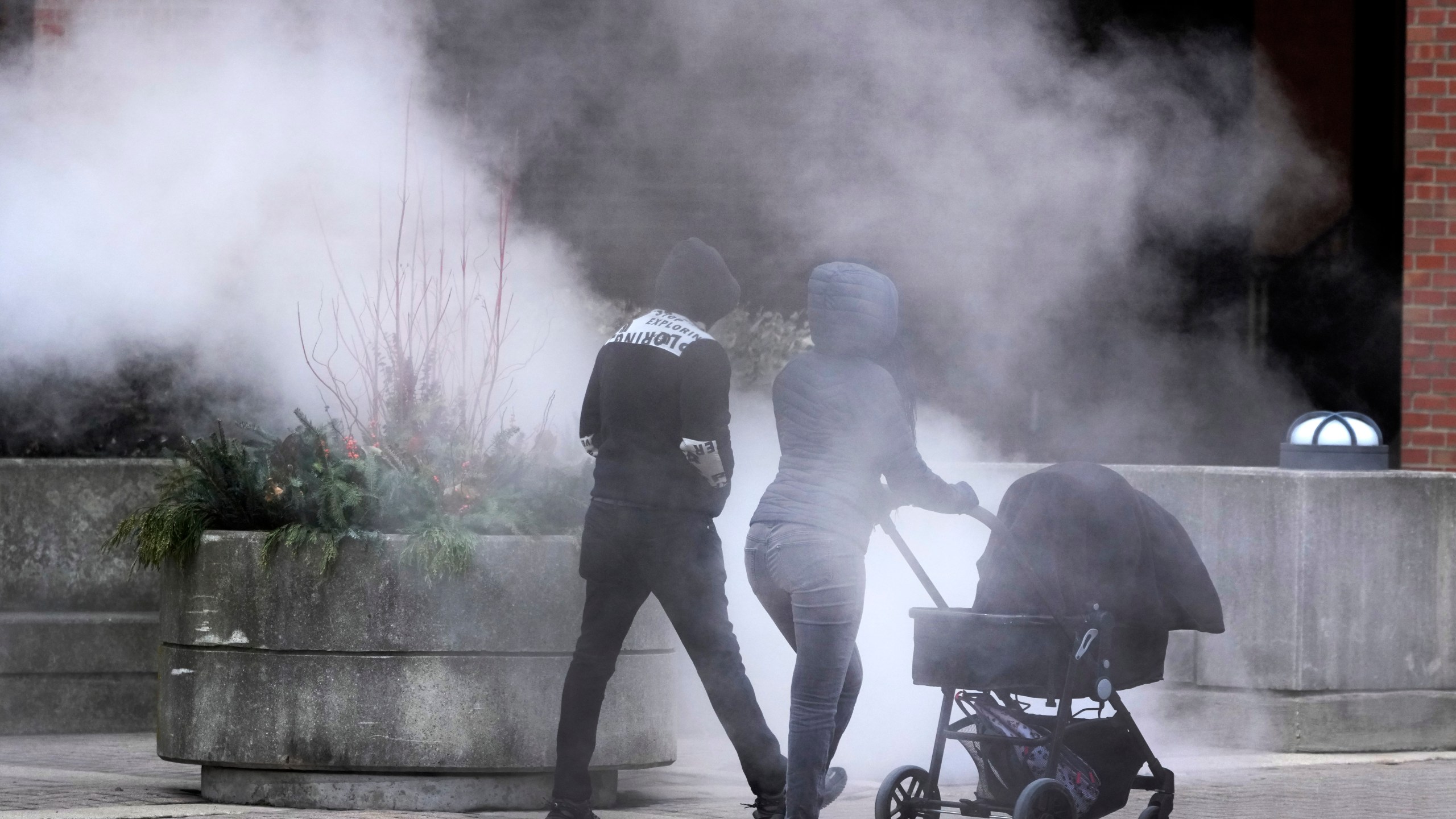 A couple push a baby carriage past steam released in the air as an Arctic blast brings single-digit temperatures with wind chills below zero on Thursday, Dec. 12, 2024, in Chicago. (AP Photo/Charles Rex Arbogast)