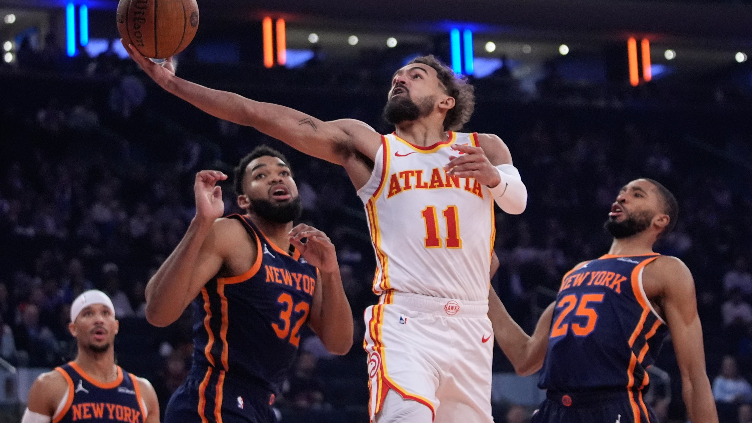 Atlanta Hawks' Trae Young (11) drives past New York Knicks' Mikal Bridges (25), Karl-Anthony Towns (32) and Josh Hart (3) during the first half of an Emirates NBA Cup basketball game Wednesday, Dec. 11, 2024, in New York. (AP Photo/Frank Franklin II)