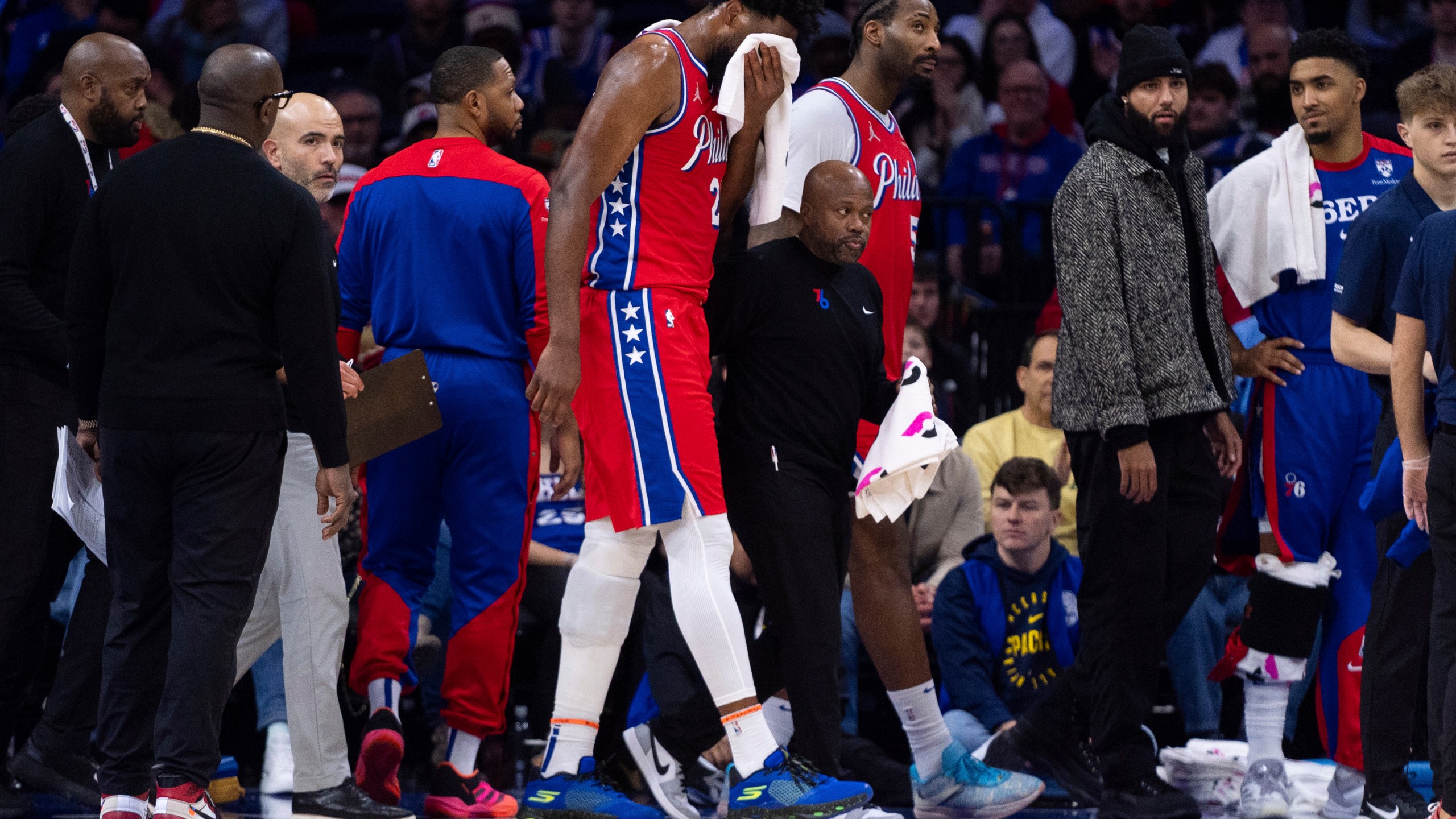 Philadelphia 76ers' Joel Embiid, center, gets helped off the court after getting hit in the face during the first half of an NBA basketball game against the Indiana Pacers, Friday, Dec. 13, 2024, in Philadelphia. (AP Photo/Chris Szagola)