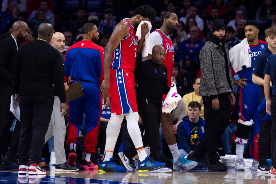 Philadelphia 76ers' Joel Embiid, center, gets helped off the court after getting hit in the face during the first half of an NBA basketball game against the Indiana Pacers, Friday, Dec. 13, 2024, in Philadelphia. (AP Photo/Chris Szagola)