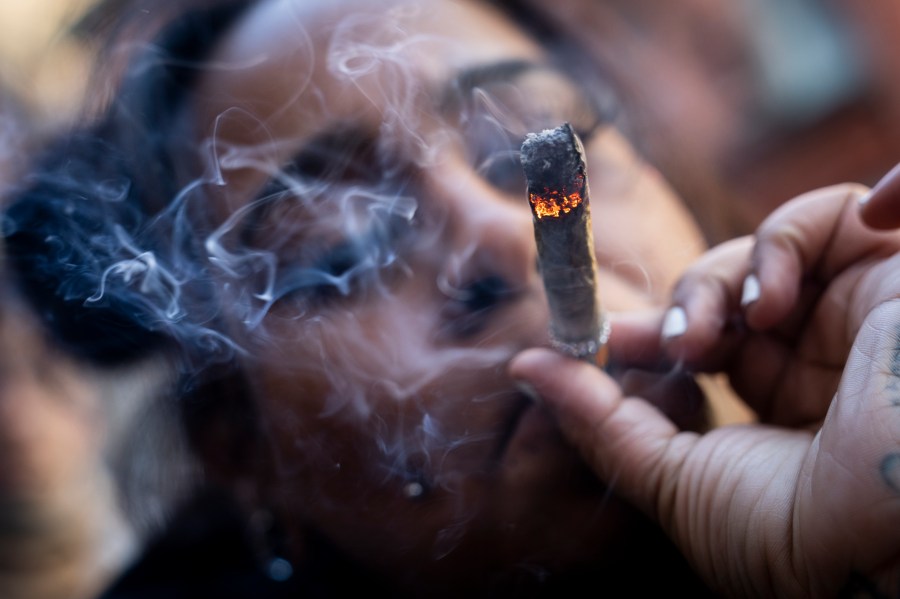 FILE - A person smokes cannabis outside the Smacked "pop up" cannabis dispensary location, Tuesday, Jan. 24, 2023, in New York. (AP Photo/John Minchillo, File)