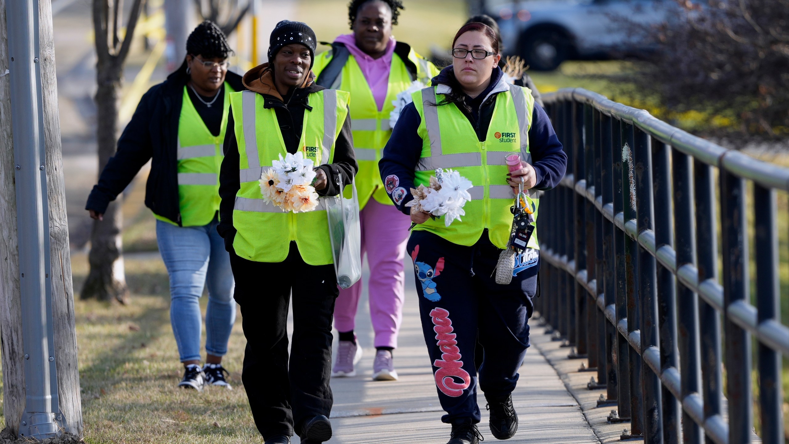 A group makes their way to leave flowers outside the Abundant Life Christian School Tuesday, Dec. 17, 2024 in Madison, Wis., following a shooting on Monday. (AP Photo/Morry Gash)