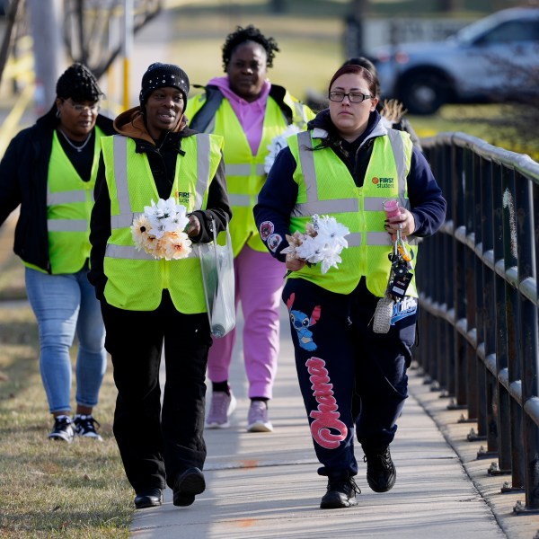 A group makes their way to leave flowers outside the Abundant Life Christian School Tuesday, Dec. 17, 2024 in Madison, Wis., following a shooting on Monday. (AP Photo/Morry Gash)