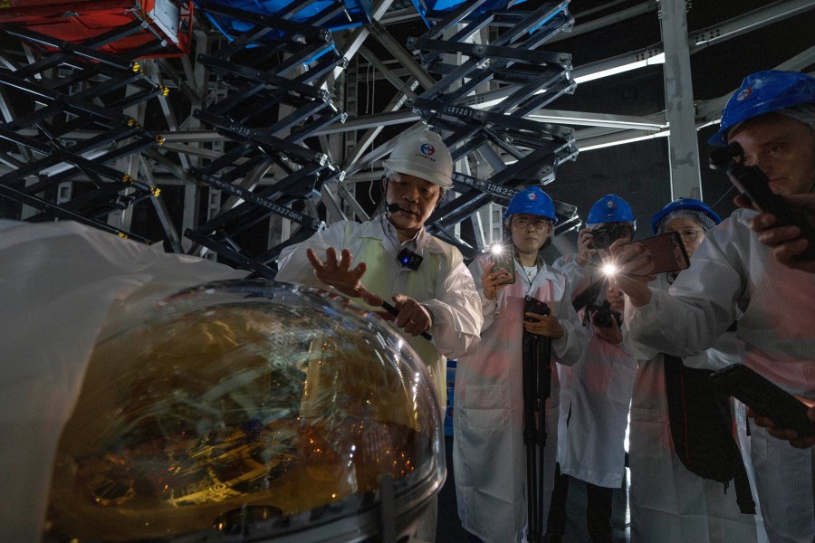 Wang Yifang, chief scientist and project manager at the Jiangmen Underground Neutrino Observatory briefs visitors on a Photomultiplier Tube used to convert photons into electrical signal, of which 20,000 pieces are used in the cosmic detector located 2297 feet (700 meters) underground in Kaiping, southern China's Guangdong province on Friday, Oct. 11, 2024. (AP Photo/Ng Han Guan)