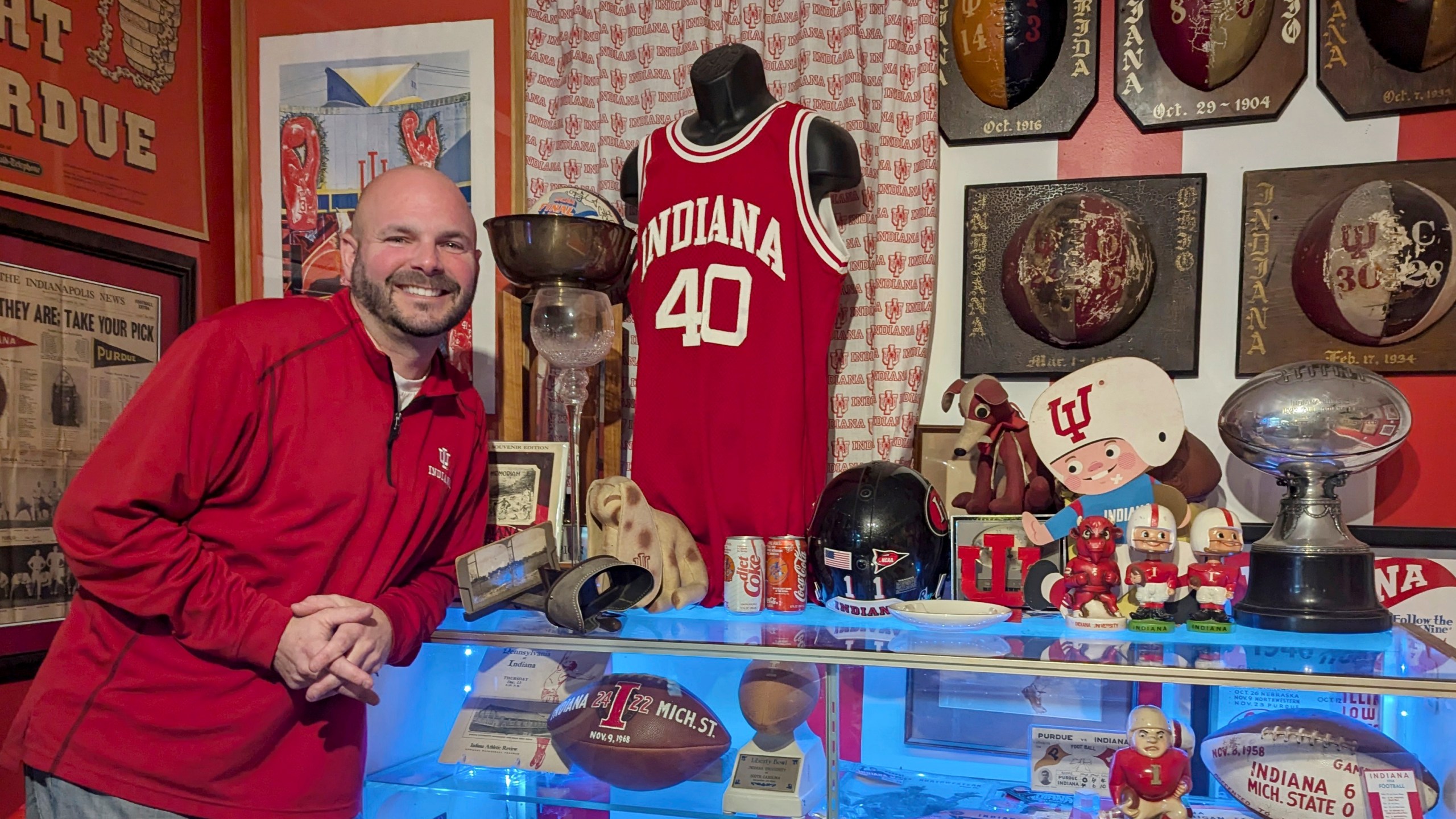 In this photo provided by Heather White, Indiana Hoosiers fan Brett White pose Monday, Dec. 16, 2024, at his home in Bloomington, Ind. White and other Indiana fans are riding the euphoria of a great season that culminated in a berth in the College Football Playoff. The Hoosiers will meet Notre Dame on Friday night in South Bend, Ind. (Heather White via AP)