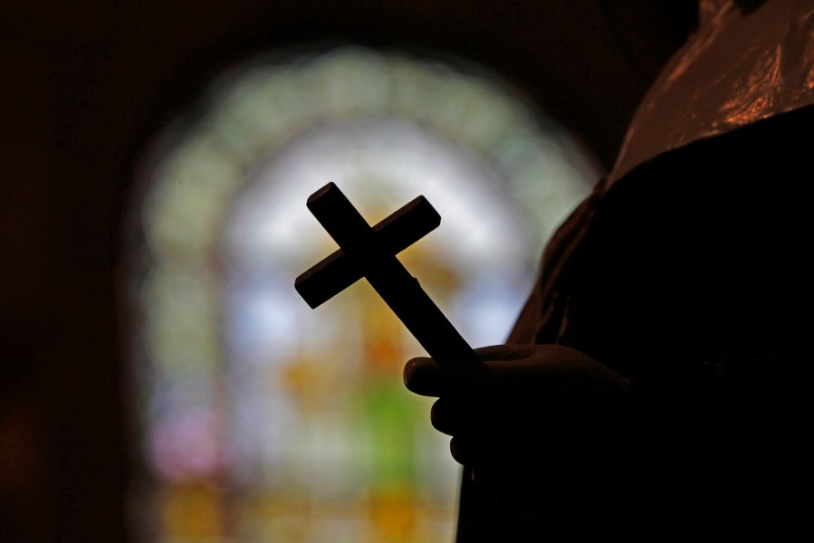 FILE - This Dec. 1, 2012 file photo shows a silhouette of a crucifix and a stained glass window inside a Catholic Church in New Orleans. (AP Photo/Gerald Herbert, File)