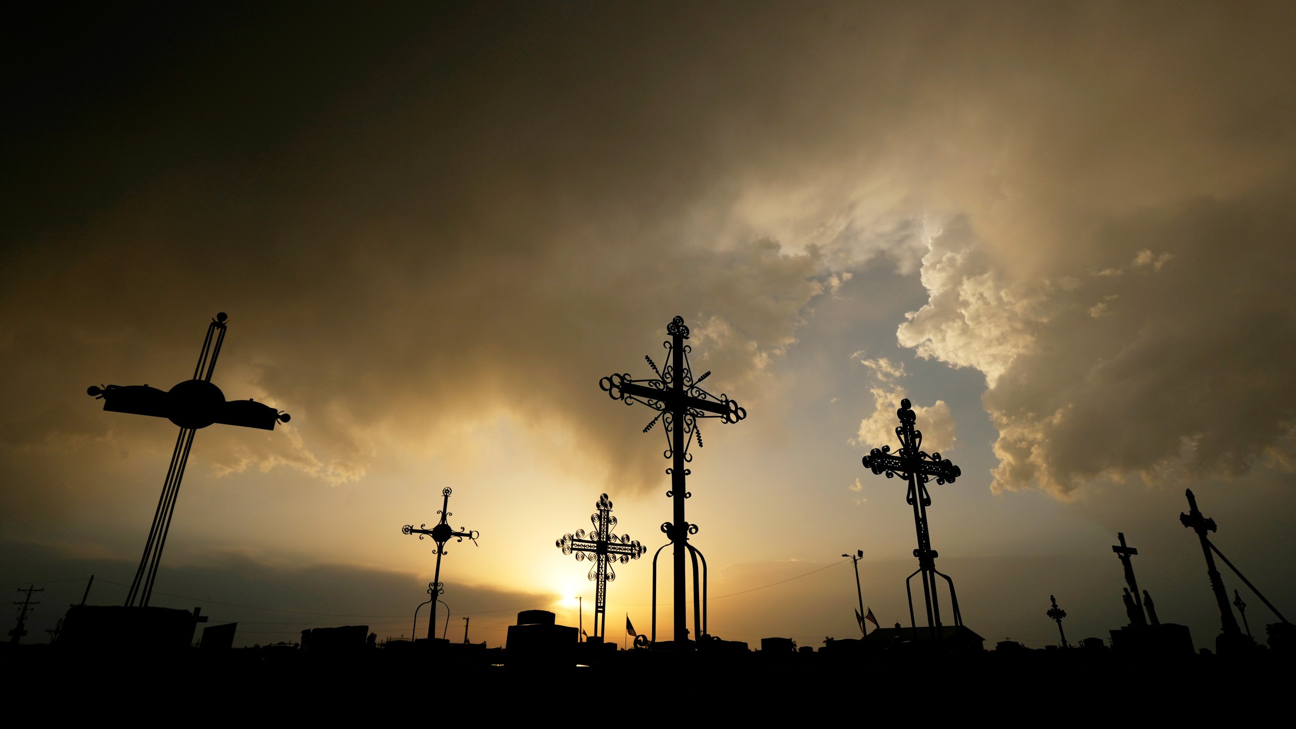 FILE - Iron crosses marking graves are silhouetted against storm clouds building over a cemetery Saturday, May 25, 2024, in Victoria, Kan. (AP Photo/Charlie Riedel, File)