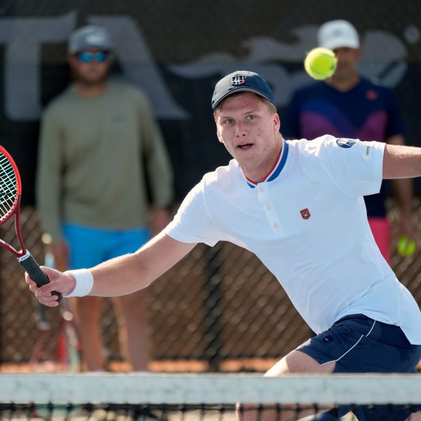 Tennis player Jenson Brooksby practices at the USTA national campus while his coaches Rhyne Williams, back left, and Eric Nunez watch, Tuesday, Dec. 10, 2024, in Orlando, Fla. (AP Photo/John Raoux)