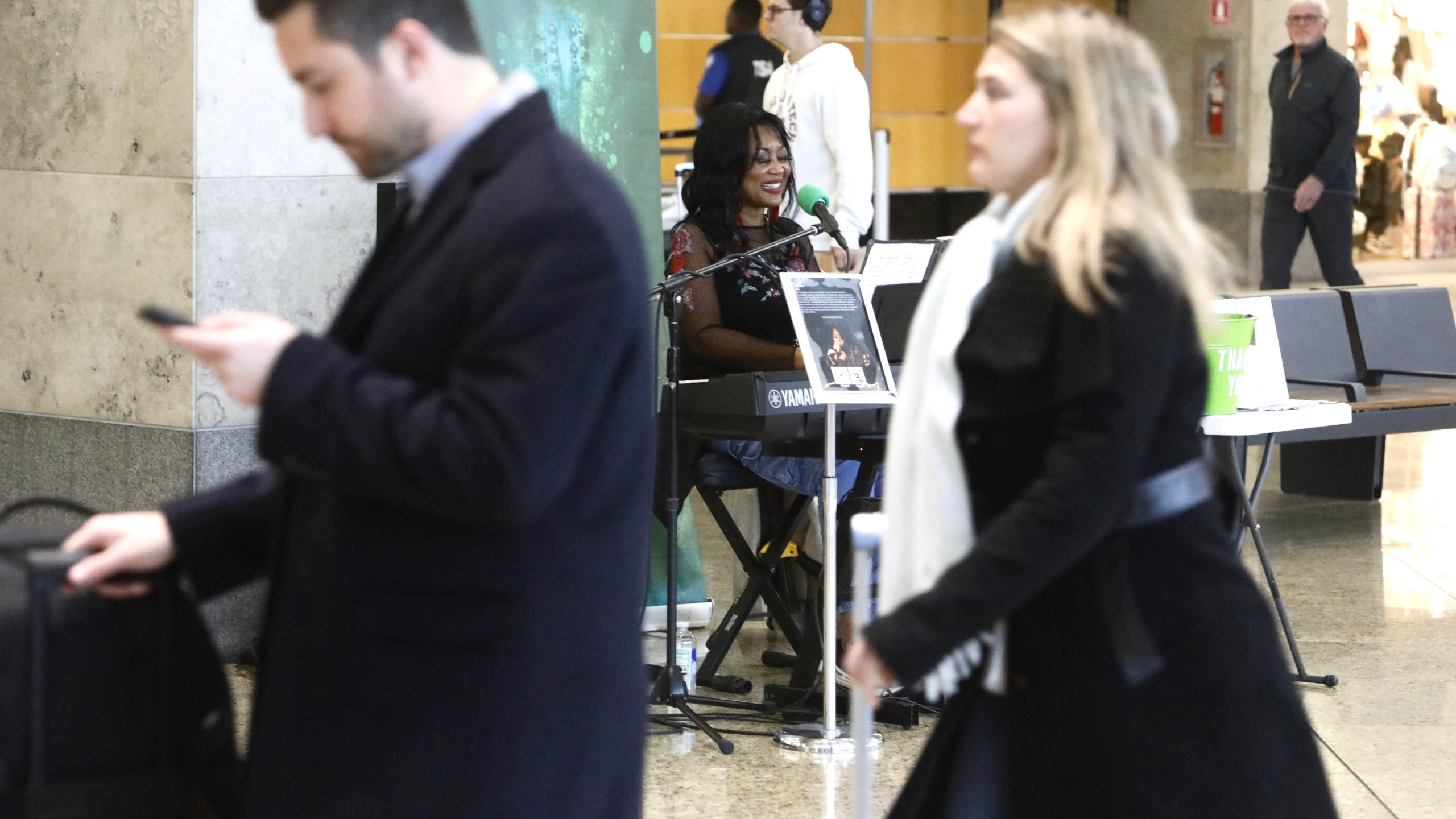 Roz McCommon, center, performs amid travelers at Seattle-Tacoma International Airport on November 26, 2024, in SeaTac, Wash. (AP Photo/Manual Valdes)