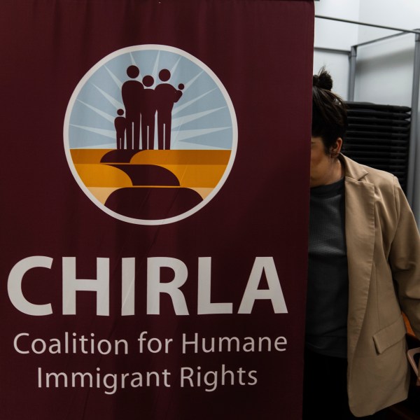 Elizabeth Rodriguez, digital content creator at the Coalition for Humane Immigrant Rights, sets up a banner for a bilingual workshop for immigrants who want to stay in the United States in Los Angeles, Wednesday, Dec. 4, 2024. (AP Photo/Jae C. Hong)