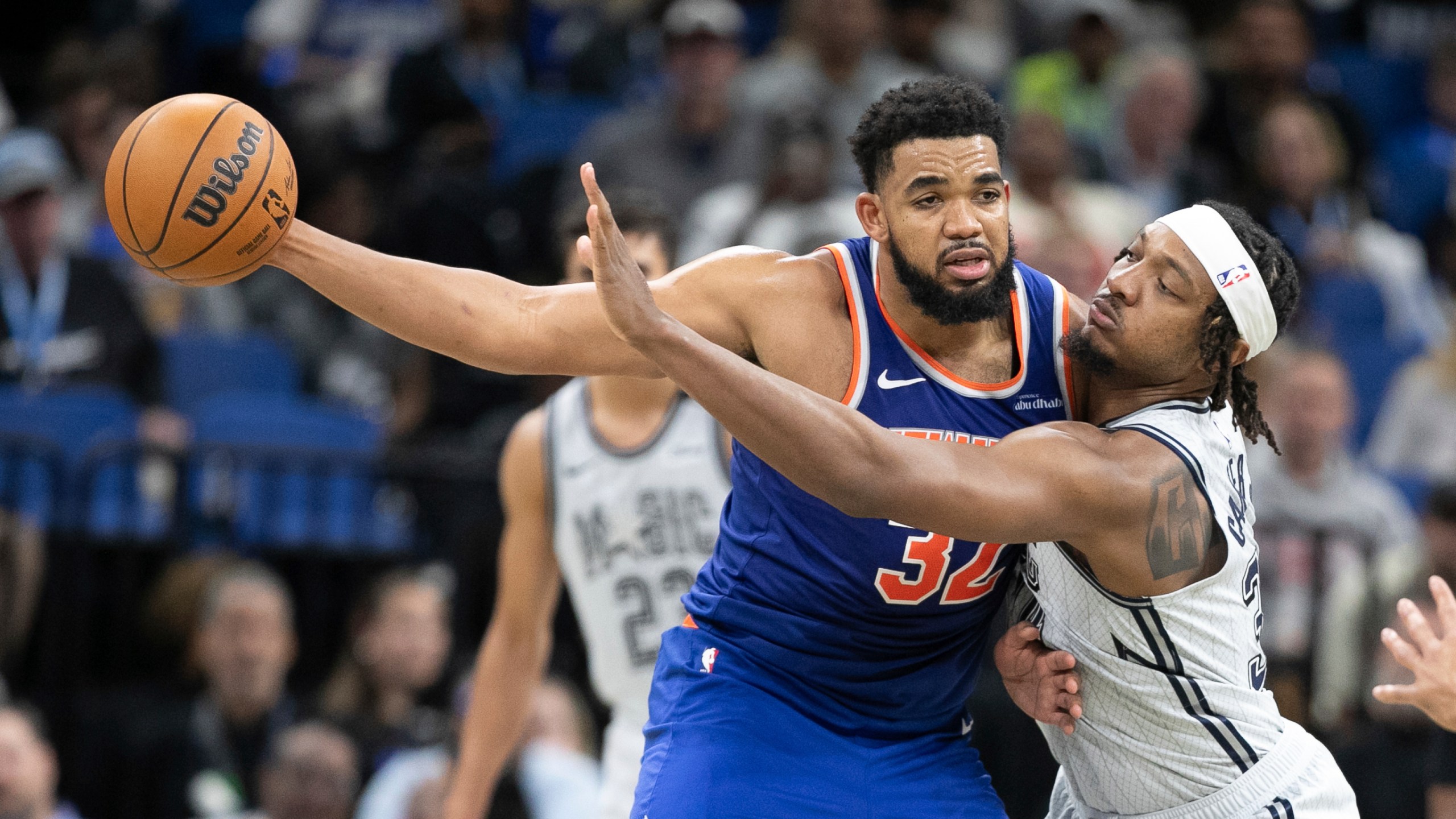 New York Knicks center Karl-Anthony Towns (32) is pressured by Orlando Magic center Wendell Carter Jr., right, during the second half of an NBA basketball game Sunday, Dec. 15, 2024, in Orlando, Fla. (AP Photo/Alan Youngblood)