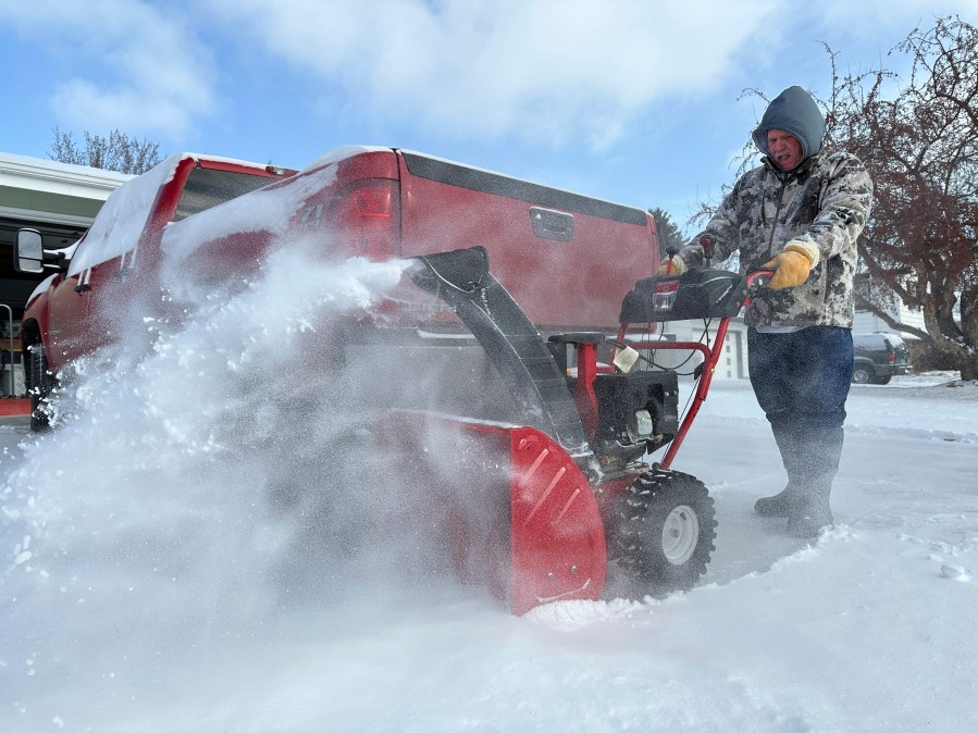 Jim Thom clears his driveway of snow with a snowblower on Thursday, Dec. 19, 2024, in Bismarck, N.D. (AP Photo/Jack Dura)