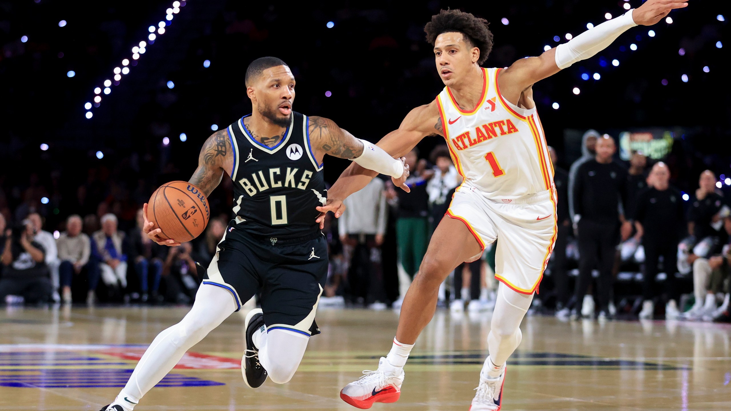 Milwaukee Bucks guard Damian Lillard (0) drives past Atlanta Hawks forward Jalen Johnson (1) during the second half of a semifinal game in the NBA Cup basketball tournament Saturday, Dec. 14, 2024, in Las Vegas. (AP Photo/Ian Maule)