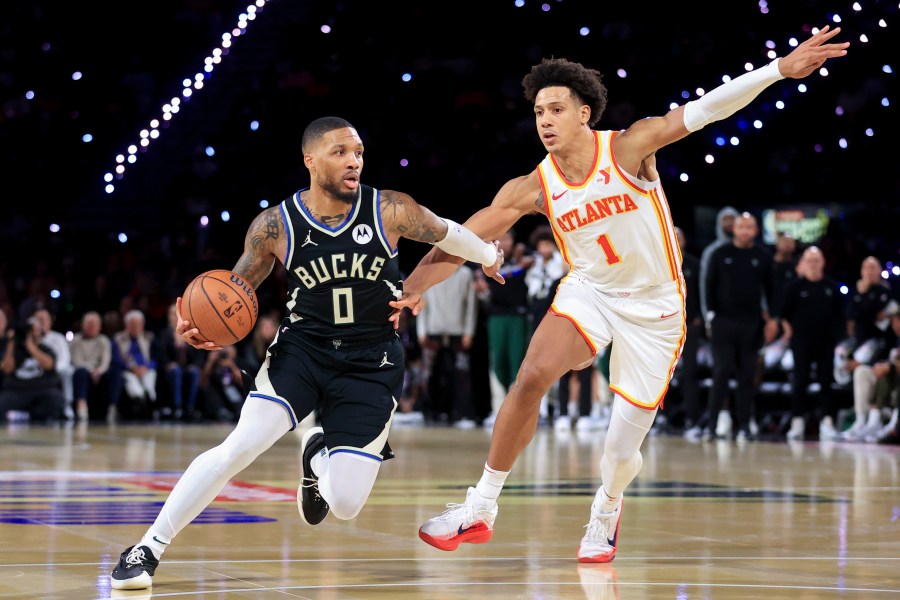 Milwaukee Bucks guard Damian Lillard (0) drives past Atlanta Hawks forward Jalen Johnson (1) during the second half of a semifinal game in the NBA Cup basketball tournament Saturday, Dec. 14, 2024, in Las Vegas. (AP Photo/Ian Maule)