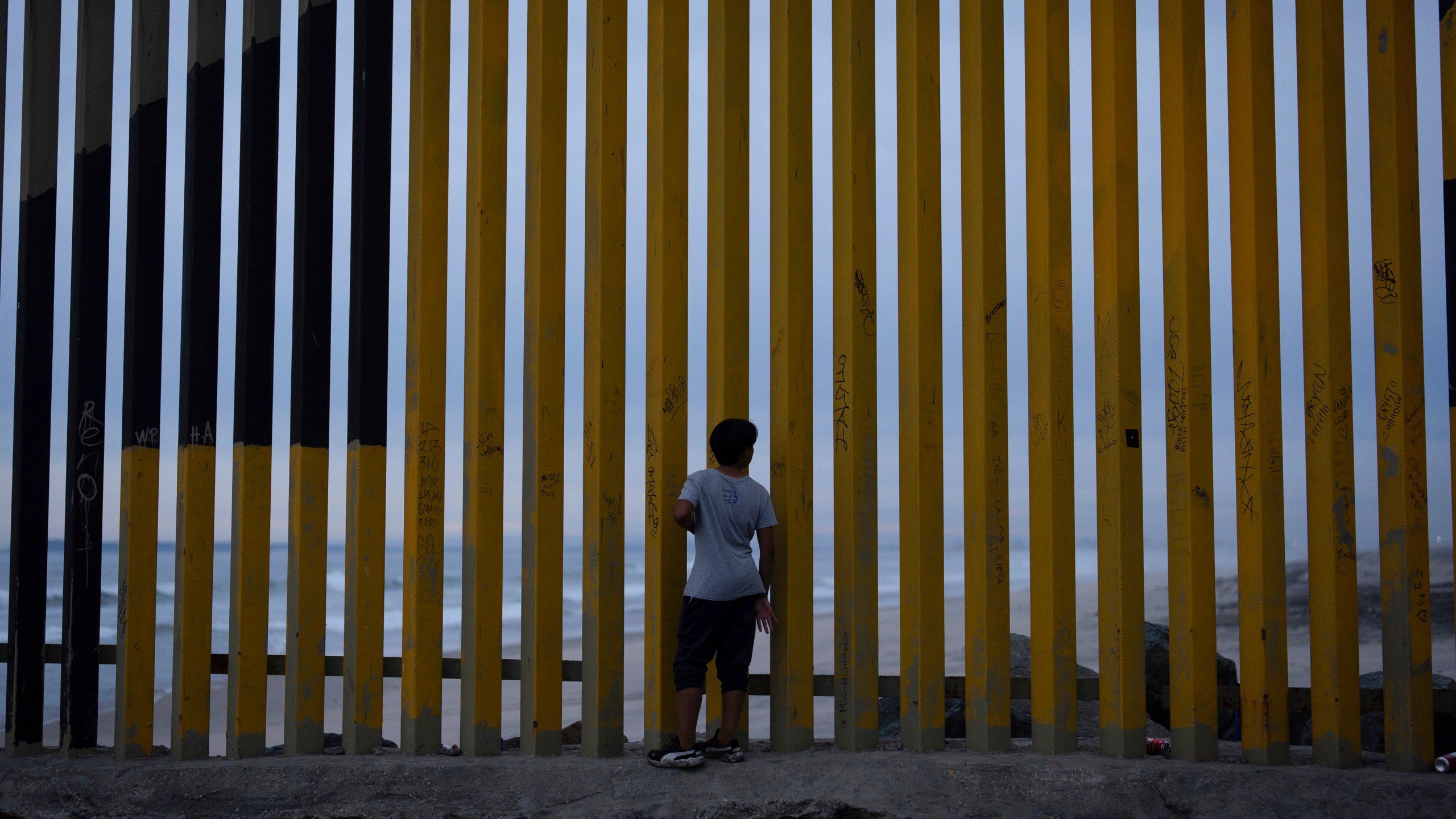 FILE - A boy looks through a border wall separating Mexico from the United States, Nov. 26, 2024, in Tijuana, Mexico. (AP Photo/Gregory Bull, File)