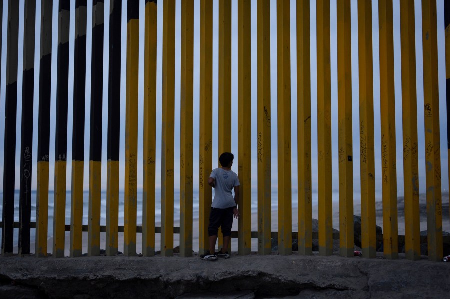 FILE - A boy looks through a border wall separating Mexico from the United States, Nov. 26, 2024, in Tijuana, Mexico. (AP Photo/Gregory Bull, File)