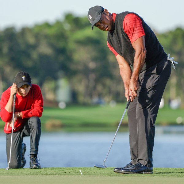 Charlie Woods, left, watches his father Tiger Woods, right, watches during the final round of the PNC Championship golf tournament, Dec. 18, 2022, in Orlando, Fla. (AP Photo/Kevin Kolczynski)