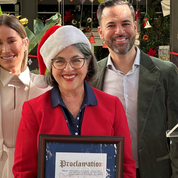 Miami-Dade County Mayor Daniella Levine Cava presents a proclamation pardoning 4-month-old pigs Glinda and Elphaba from being roasted during Cuban Americans' upcoming Christmas Eve celebrations, to restaurant owners Erica and Kali Castellanos outside their Latin Café 2000 restaurant in Miami, Friday, Dec. 20, 2024. (AP Photo/Terry Spencer)