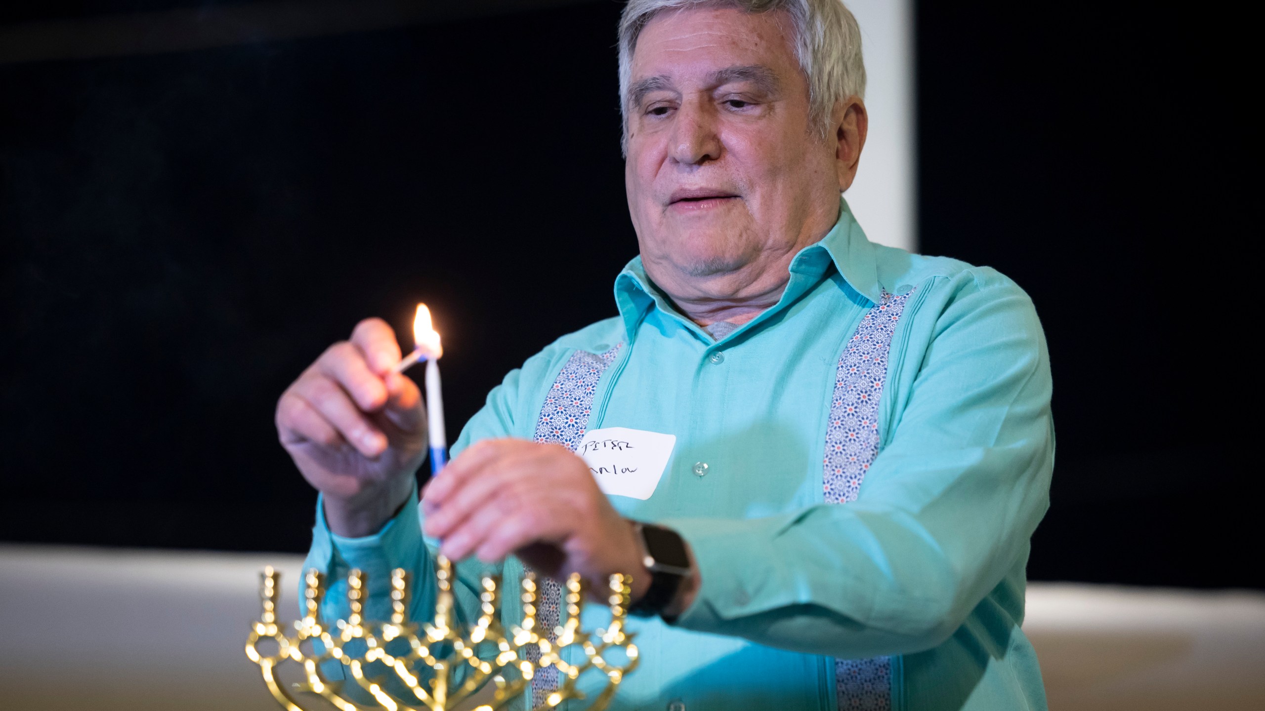 Rabbi Peter Tarlow lights a candle on a menorah during a Chicanukah event at Holocaust Museum Houston on Thursday, Dec. 19, 2024, in Houston. (AP Photo/Annie Mulligan)