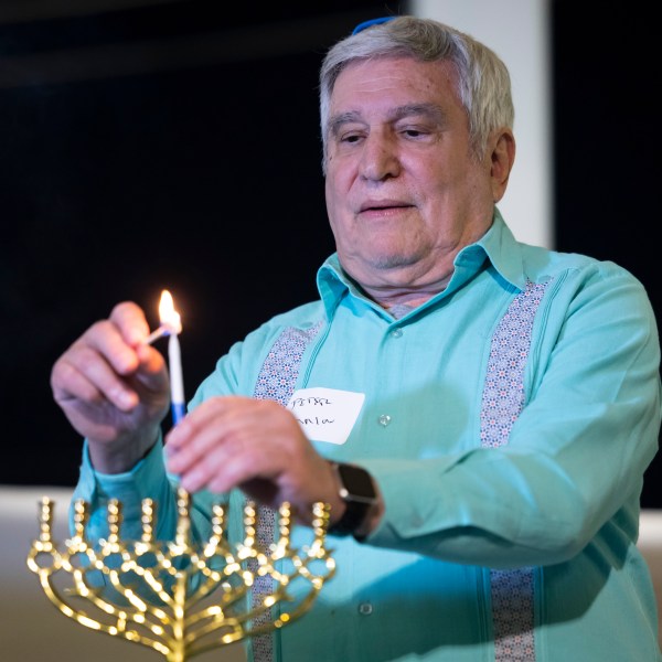 Rabbi Peter Tarlow lights a candle on a menorah during a Chicanukah event at Holocaust Museum Houston on Thursday, Dec. 19, 2024, in Houston. (AP Photo/Annie Mulligan)