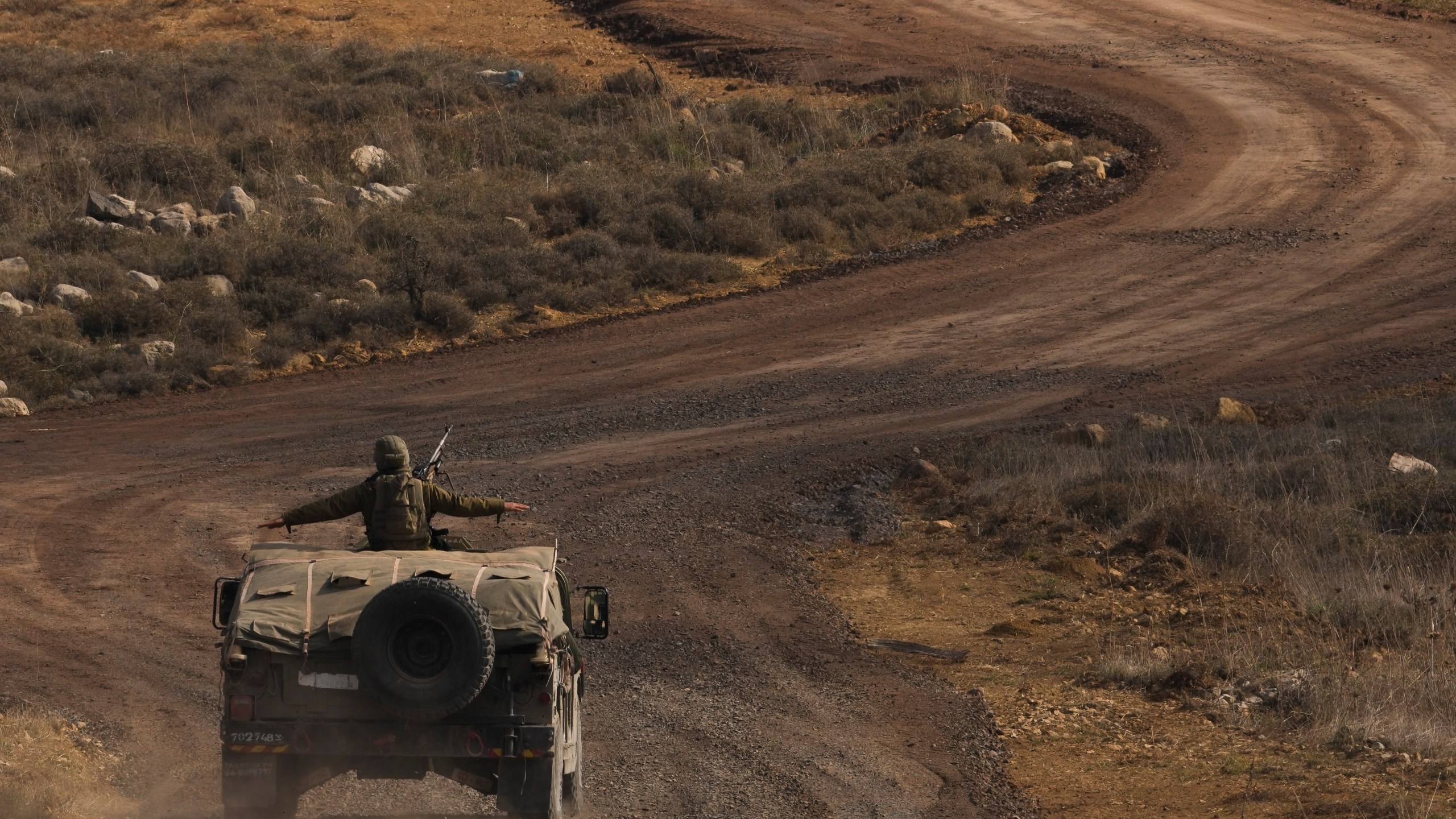 An Israeli soldier stands on an armoured vehicle on the buffer zone after crossing the security fence near the so-called Alpha Line that separates the Israeli-controlled Golan Heights from Syria, viewed from the town of Majdal Shams, Saturday, Dec. 21, 2024. (AP Photo/Matias Delacroix)