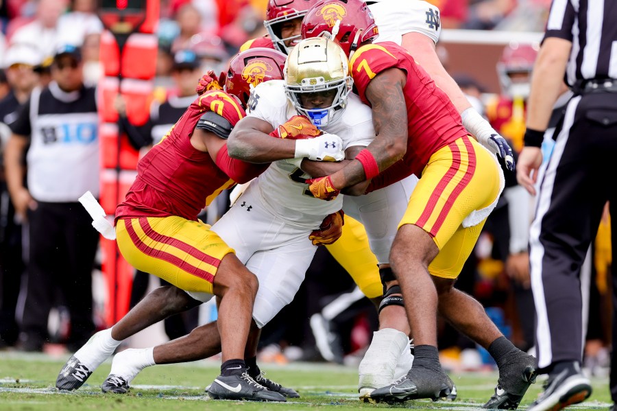 Notre Dame running back Jeremiyah Love, center, is tackled by Southern California safetys Akili Arnold, left, and Kamari Ramsey during the first half of an NCAA college football game against Southern California, Saturday, Nov. 30, 2024, in Los Angeles. (AP Photo/Ryan Sun)