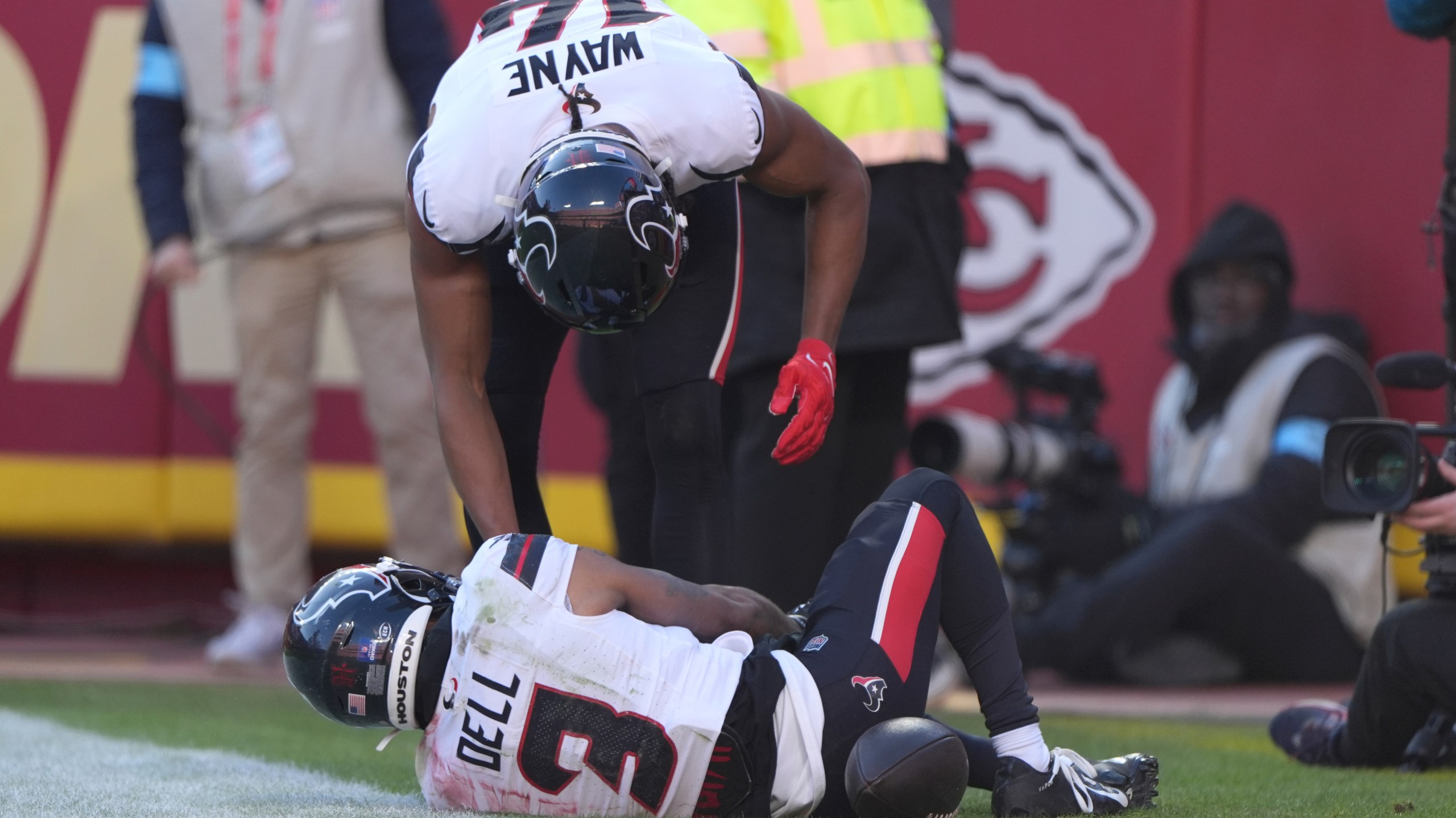 Houston Texans wide receiver Tank Dell, grabs his knee while being checked on by teammate Jared Wayne after catching a touchdown pass during the second half of an NFL football game Saturday, Dec. 21, 2024, in Kansas City, Mo. (AP Photo/Charlie Riedel)