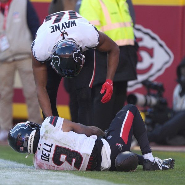 Houston Texans wide receiver Tank Dell, grabs his knee while being checked on by teammate Jared Wayne after catching a touchdown pass during the second half of an NFL football game Saturday, Dec. 21, 2024, in Kansas City, Mo. (AP Photo/Charlie Riedel)