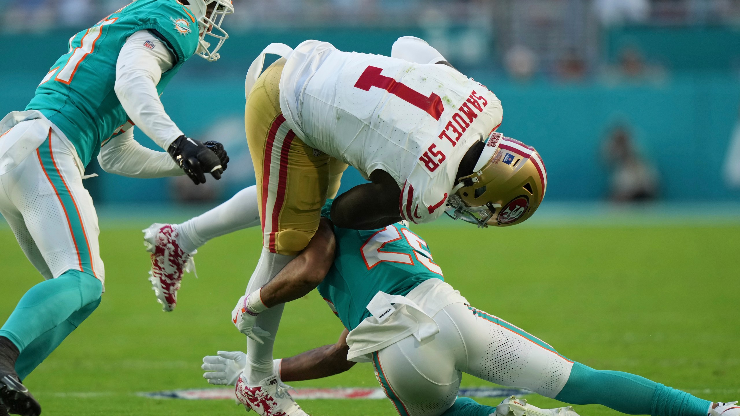 San Francisco 49ers wide receiver Deebo Samuel Sr. (1) is tackled by Miami Dolphins running back Jaylen Wright (25) during the first half of an NFL football game, Sunday, Dec. 22, 2024, in Miami Gardens, Fla. (AP Photo/Lynne Sladky)