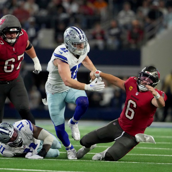 Dallas Cowboys linebacker Micah Parsons (11) strips the ball away from Tampa Bay Buccaneers quarterback Baker Mayfield (6) as Nick Vigil (41) attempts to recover the ball that fell out-of-bounds in the second half of an NFL football game in Arlington, Texas, Sunday, Dec. 22, 2024. (AP Photo/Jeffrey McWhorter)