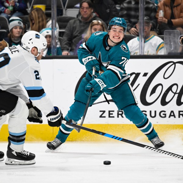 San Jose Sharks center Macklin Celebrini (71) crosses the puck against Utah Hockey Club defenseman Ian Cole (28) during the first period of an NHL hockey game Saturday, Dec. 14, 2024, in San Jose, Calif. (AP Photo/Eakin Howard)