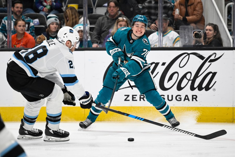 San Jose Sharks center Macklin Celebrini (71) crosses the puck against Utah Hockey Club defenseman Ian Cole (28) during the first period of an NHL hockey game Saturday, Dec. 14, 2024, in San Jose, Calif. (AP Photo/Eakin Howard)