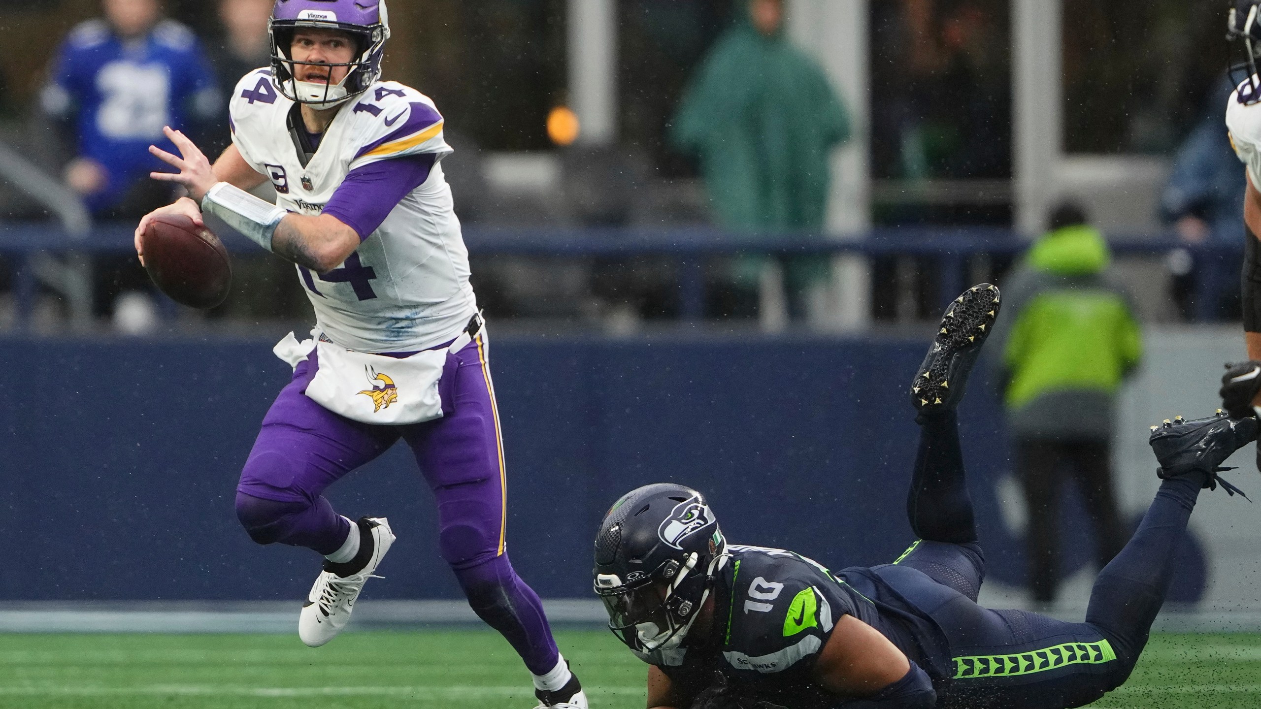 Minnesota Vikings quarterback Sam Darnold (14) scrambles as Seattle Seahawks linebacker Uchenna Nwosu (10) tries to tackle during the first half of an NFL football game, Sunday, Dec. 22, 2024, in Seattle. (AP Photo/Lindsey Wasson)