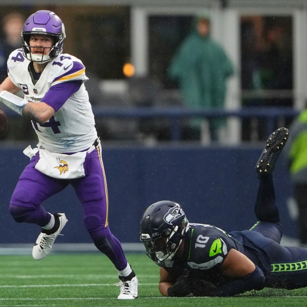 Minnesota Vikings quarterback Sam Darnold (14) scrambles as Seattle Seahawks linebacker Uchenna Nwosu (10) tries to tackle during the first half of an NFL football game, Sunday, Dec. 22, 2024, in Seattle. (AP Photo/Lindsey Wasson)