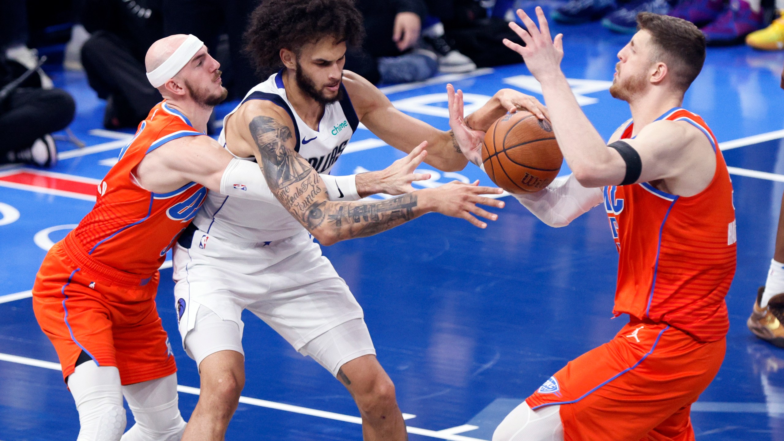 Oklahoma City Thunder center Isaiah Hartenstein, right, tries to steal the ball from Dallas Mavericks center Dereck Lively II, center, as Thunder guard Alex Caruso, left, defends during the first half of an Emirates NBA Cup basketball game, Tuesday, Dec. 10, 2024, in Oklahoma City. (AP Photo/Nate Billings)