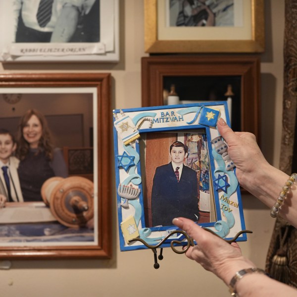 Debbie Marcus shows a framed photo of her son, Dov Marcus, taken at his Bar Mitzvah on display at their family home in Teaneck, N.J., on Friday, Dec. 20, 2024. (AP Photo/Luis Andres Henao)