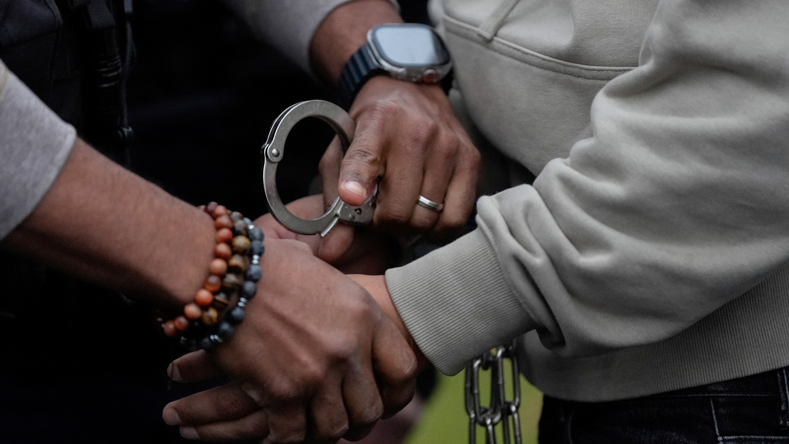 A deportation officer with Enforcement and Removal Operations in U.S. Immigration and Customs Enforcement's New York City field office changes the handcuffs of Wilmer Patricio Medina-Medina from back to front after arresting him during an early morning operation, Tuesday, Dec. 17, 2024, in the Bronx borough of New York. (AP Photo/Julia Demaree Nikhinson)