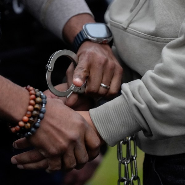 A deportation officer with Enforcement and Removal Operations in U.S. Immigration and Customs Enforcement's New York City field office changes the handcuffs of Wilmer Patricio Medina-Medina from back to front after arresting him during an early morning operation, Tuesday, Dec. 17, 2024, in the Bronx borough of New York. (AP Photo/Julia Demaree Nikhinson)