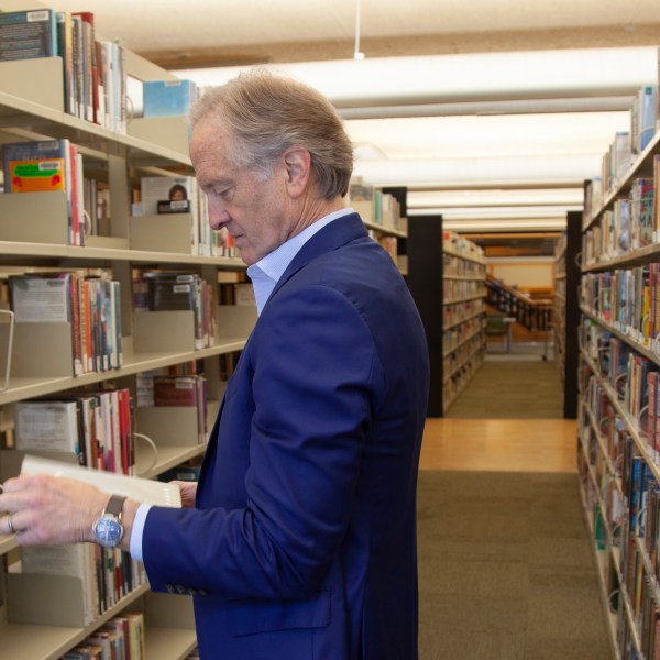 FILE - Nate Coulter, executive director of the Central Arkansas Library System (CALS), looks at a book in the main branch of the public library in downtown Little Rock, Ark., May 23, 2023. An increasing number of conservative states are pushing for measures making it easier to ban or restrict access to books. (AP Photo/Katie Adkins, File)