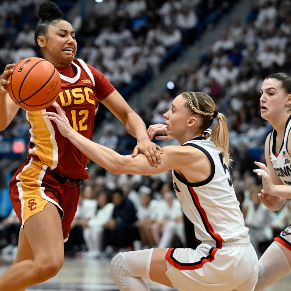 Southern California guard JuJu Watkins, left, drives to the basket as UConn guards Paige Bueckers, center, and Morgan Cheli, right, defend in the second half of an NCAA college basketball game, Saturday, Dec. 21, 2024, in Hartford, Conn. (AP Photo/Jessica Hill)